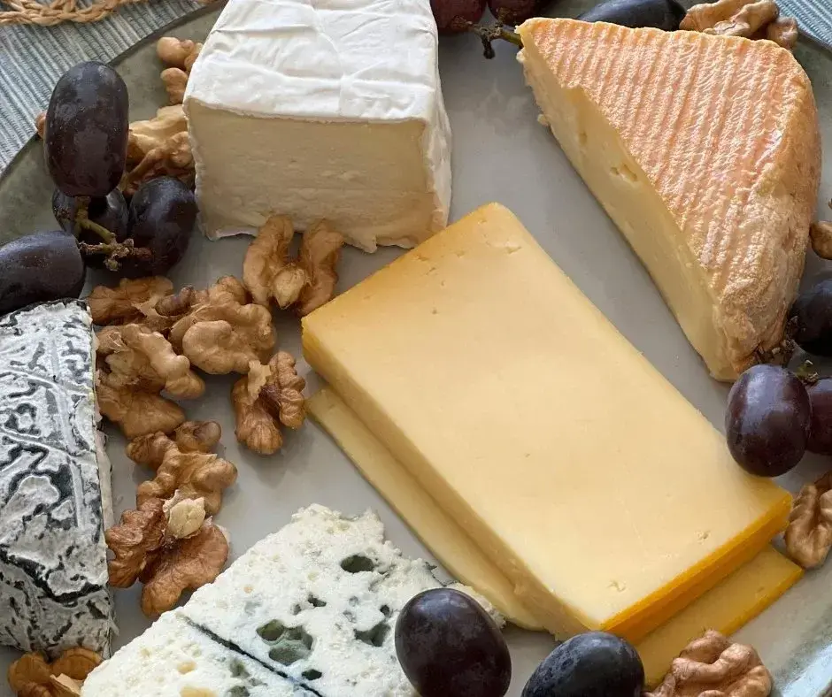 Branzeturi asezate pe un platou cu nuci si struguri