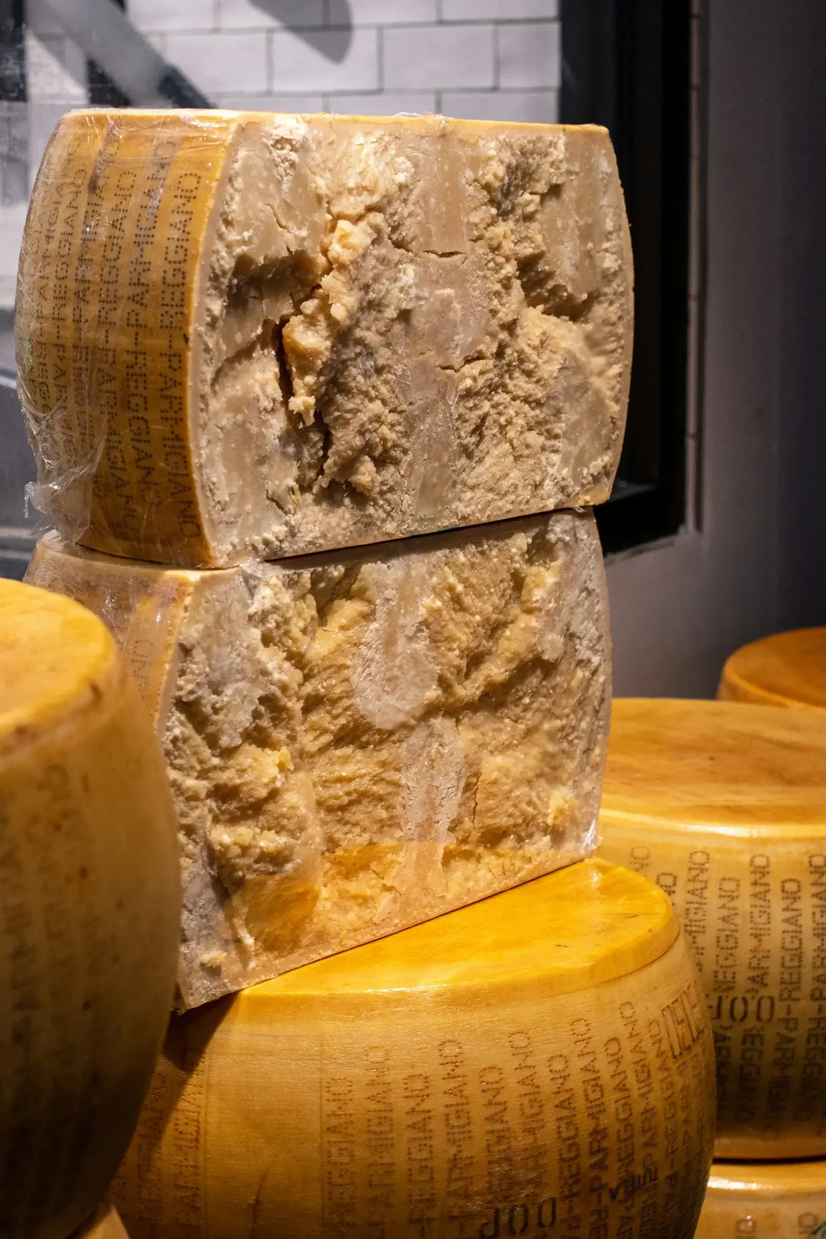 o roata de parmesan taiata in jumatate pe verticala si expusa intr-o piata de branzeturi
