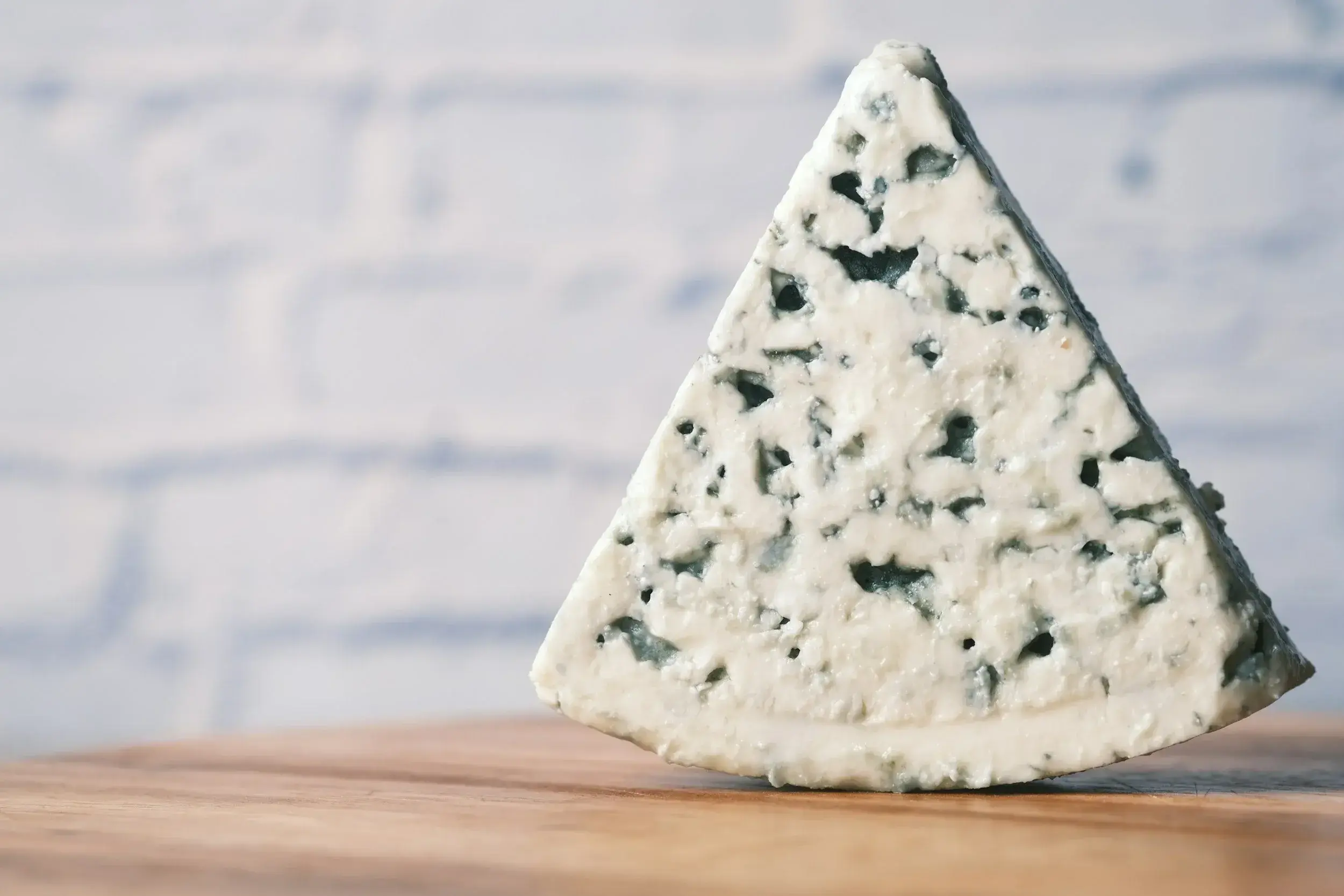 triunghi de branza Roquefort asezat vertical pe o masa de lean